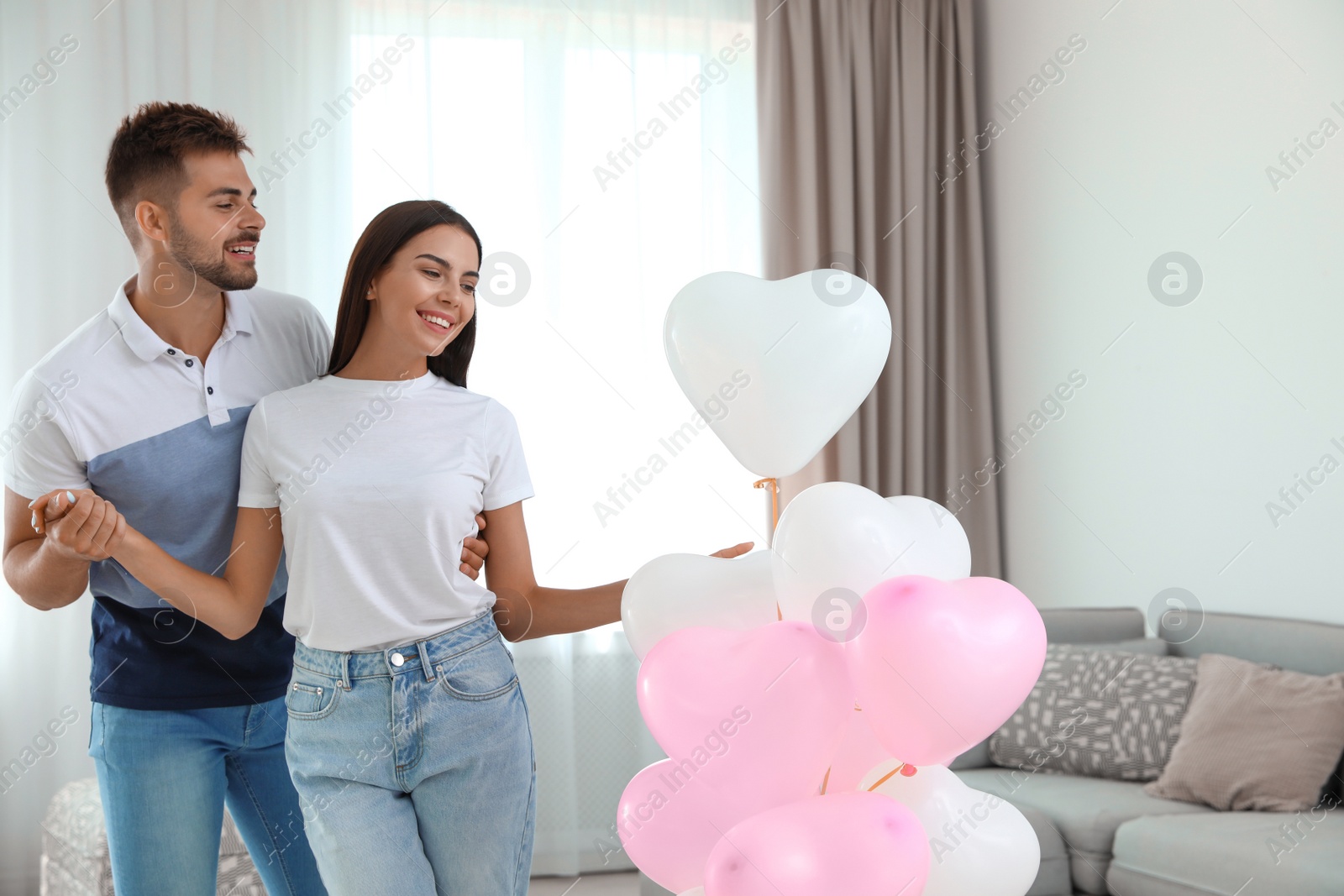 Photo of Young couple with air balloons at home. Celebration of Saint Valentine's Day