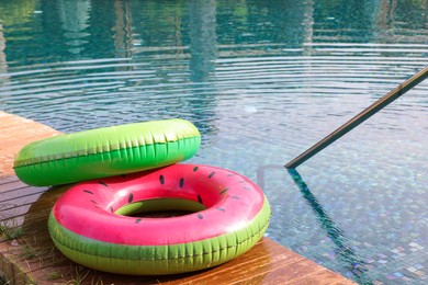 Photo of Inflatable rings on wooden deck near swimming pool. Luxury resort