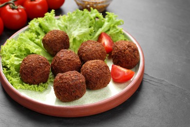 Delicious falafel balls, tomatoes and lettuce on dark table, closeup. Vegan meat products