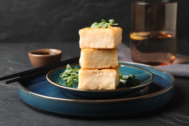 Photo of Delicious turnip cake with microgreens served on black table