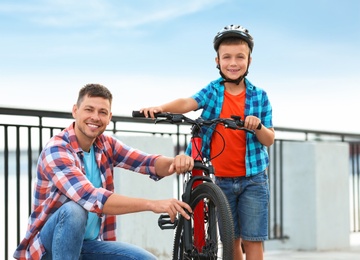 Photo of Dad and son with bicycle near river