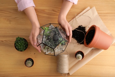 Photo of Woman taking care of home plants at wooden table, top view