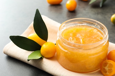 Photo of Delicious kumquat jam and fresh fruits on table, closeup