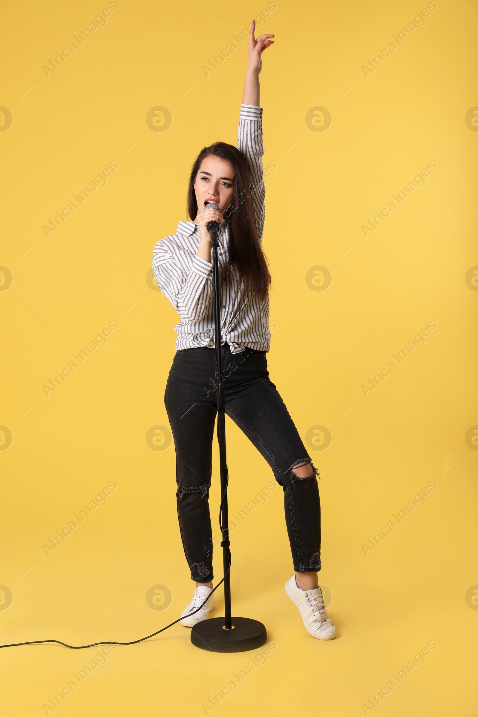 Photo of Young woman wearing casual clothes singing in microphone on color background