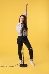 Photo of Young woman wearing casual clothes singing in microphone on color background