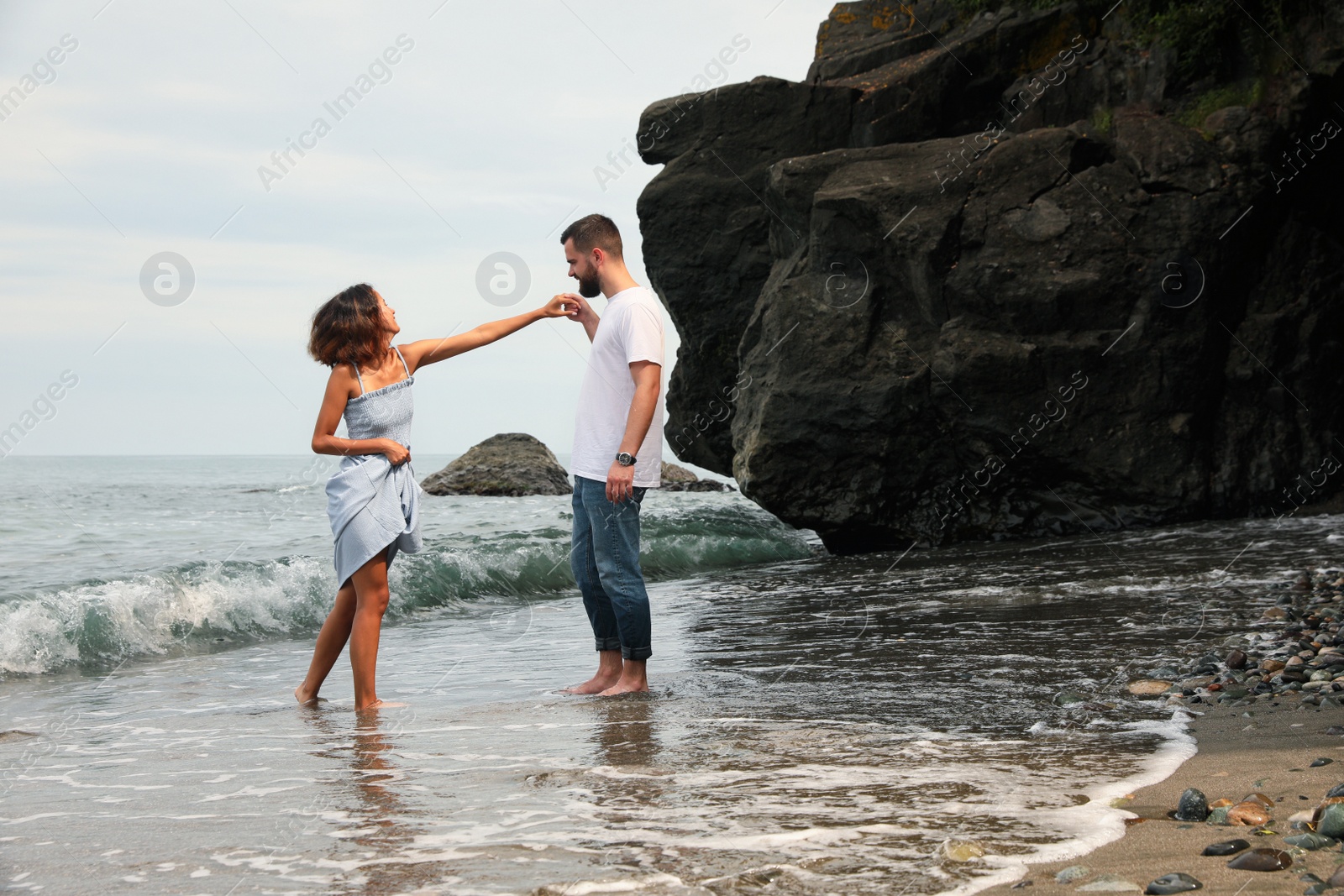 Photo of Happy young couple having fun on beach near sea, space for text