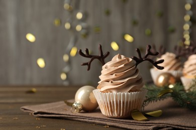 Photo of Tasty Christmas cupcake with chocolate reindeer antlers on wooden table. Space for text