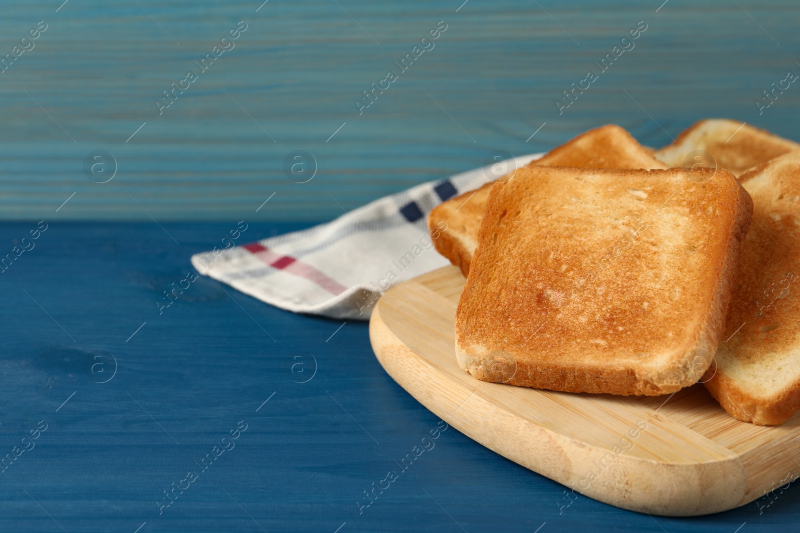 Photo of Slices of tasty toasted bread on blue wooden table. Space for text