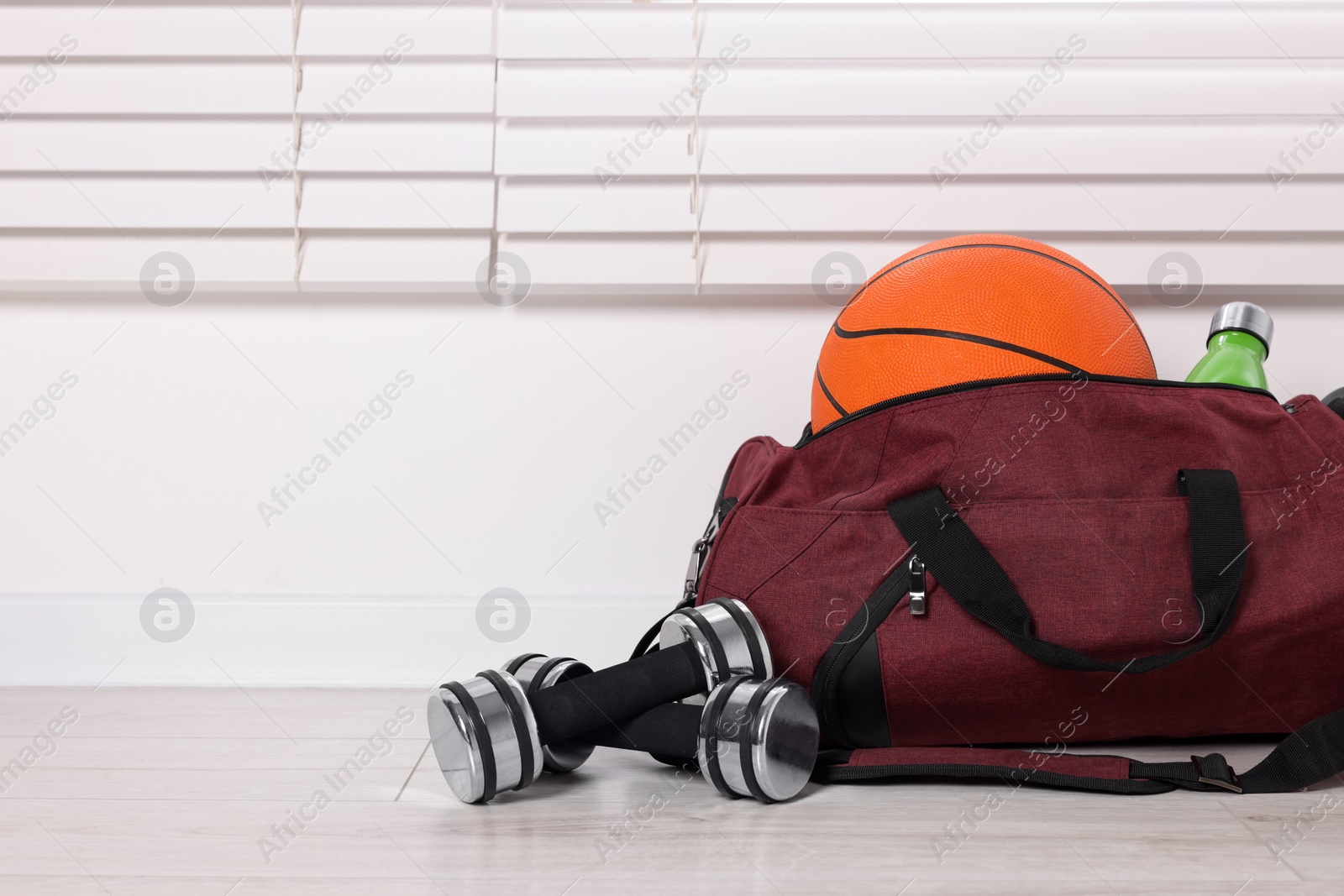 Photo of Gym bag and sports equipment on floor indoors. Space for text