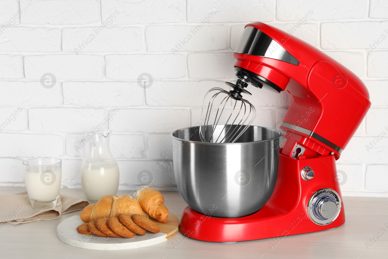 Photo of Modern red stand mixer, croissant and cookies on white wooden table, space for text