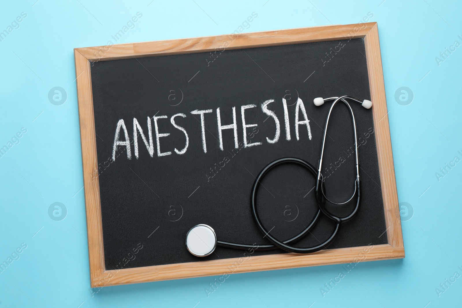 Photo of Blackboard with word Anesthesia and stethoscope on light blue background, top view