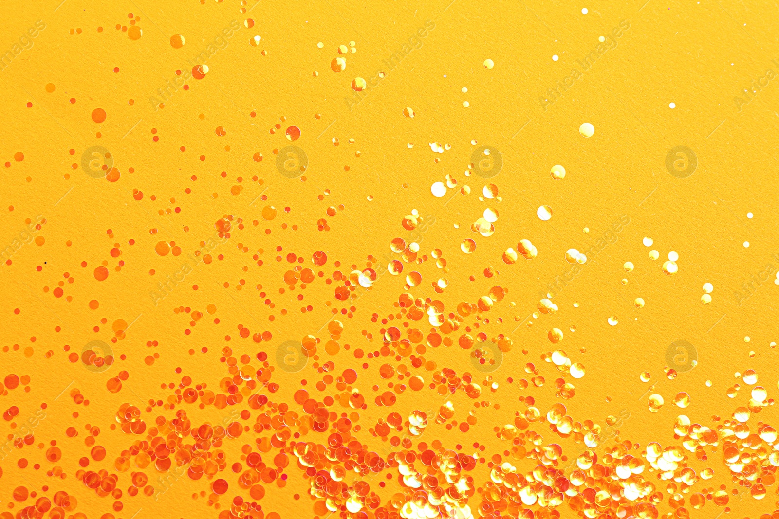 Photo of Shiny bright glitter on orange background, flat lay