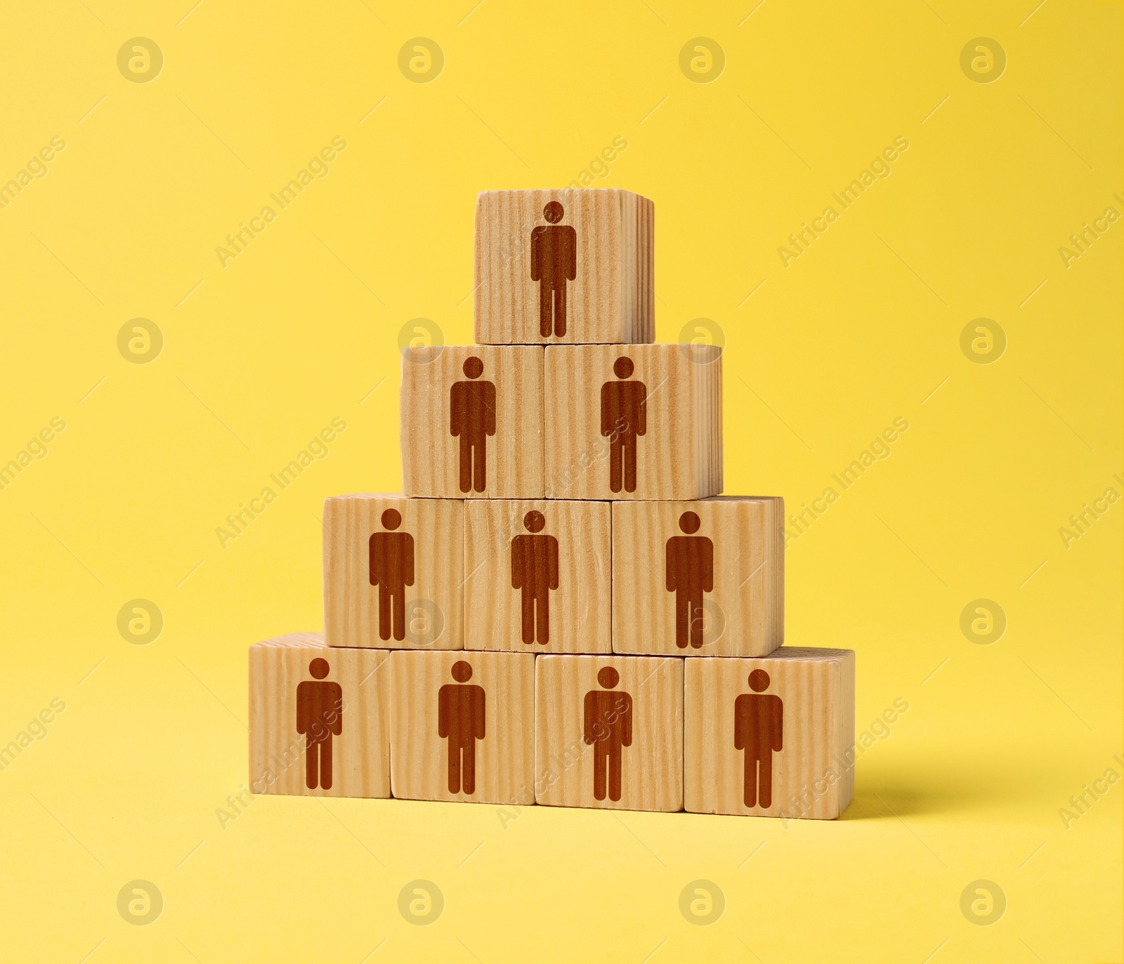 Image of Team and management concept. Pyramid of wooden cubes with human icons on yellow background