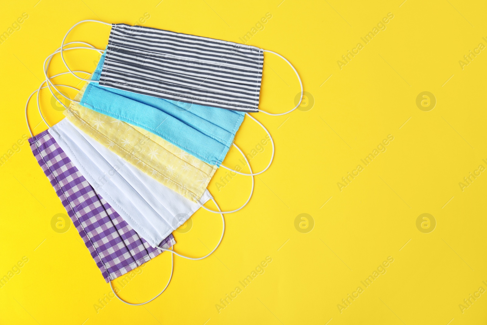 Photo of Homemade protective face masks on yellow background, flat lay. Space for text