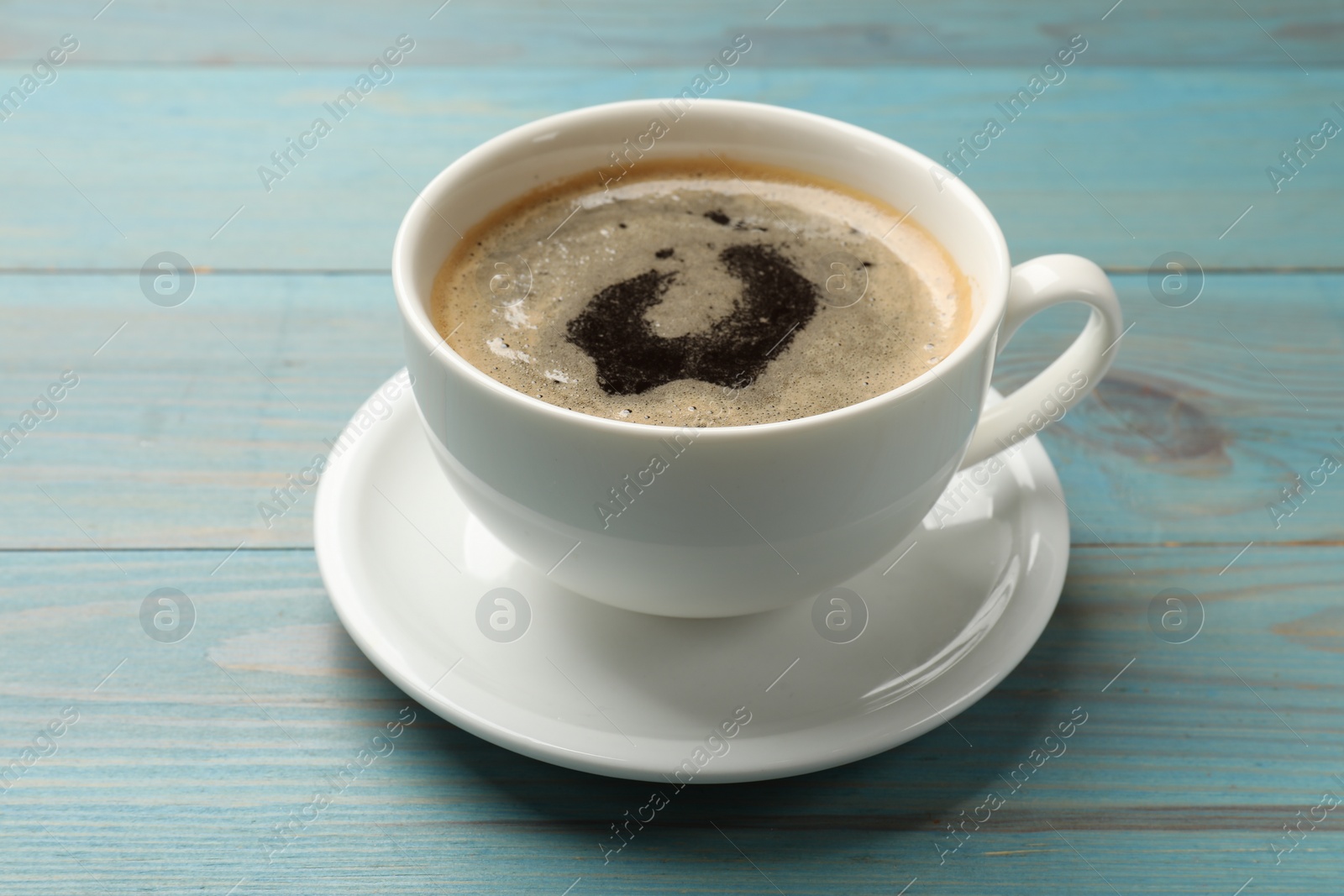 Photo of Cup of aromatic coffee on light blue wooden table, closeup