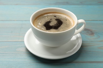 Cup of aromatic coffee on light blue wooden table, closeup