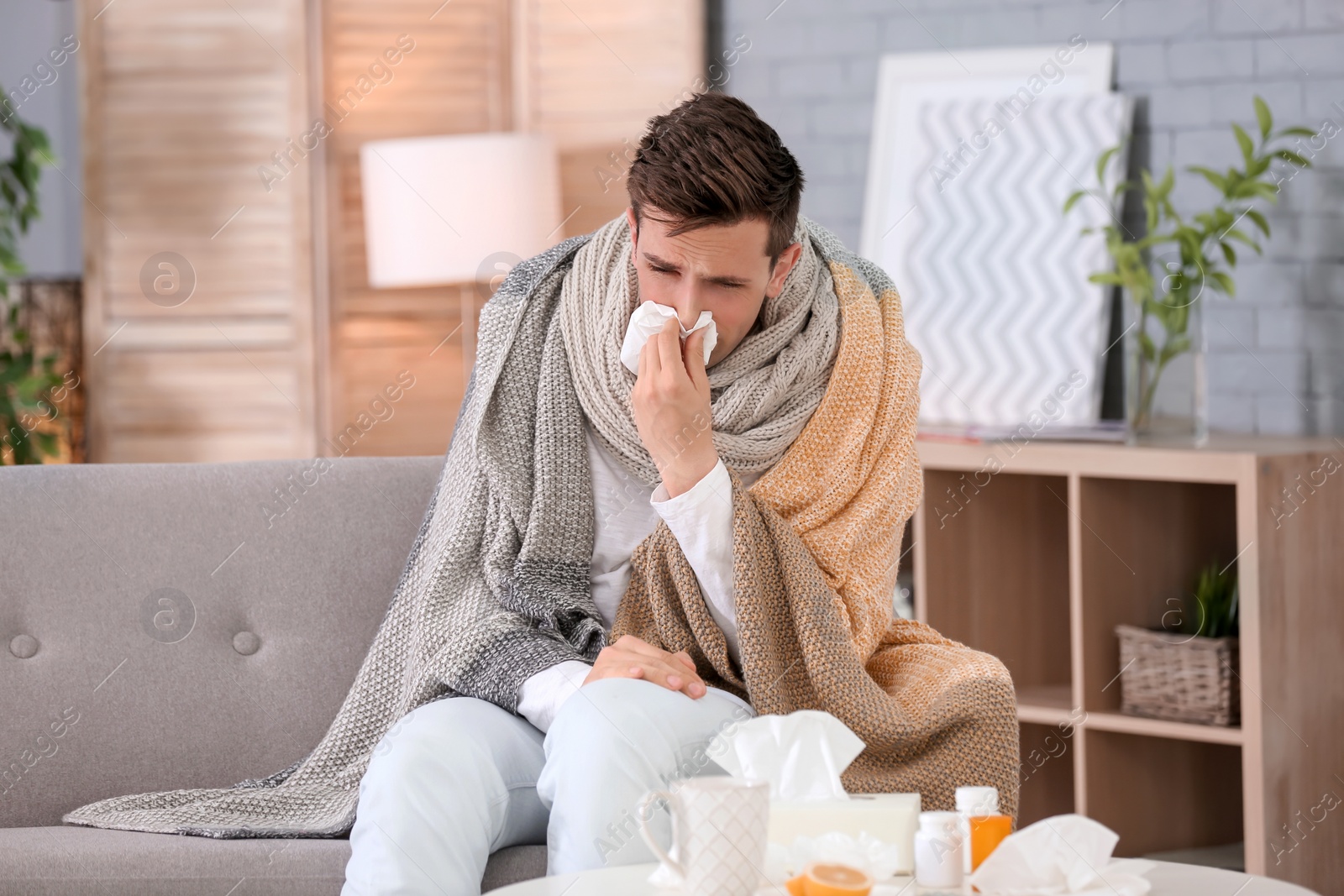 Photo of Sick young man with tissue suffering from cold at home