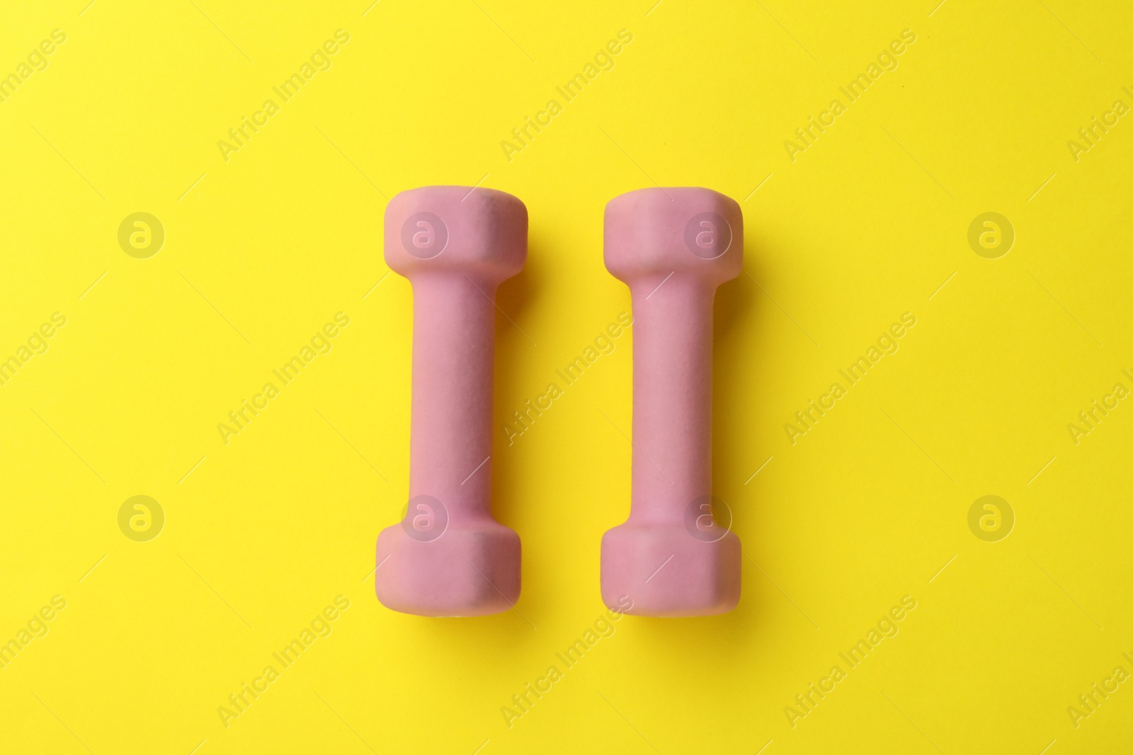 Photo of Stylish dumbbells on yellow background, flat lay