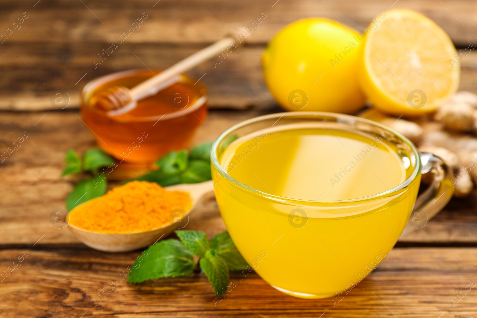 Photo of Immunity boosting drink and ingredients on wooden table, closeup