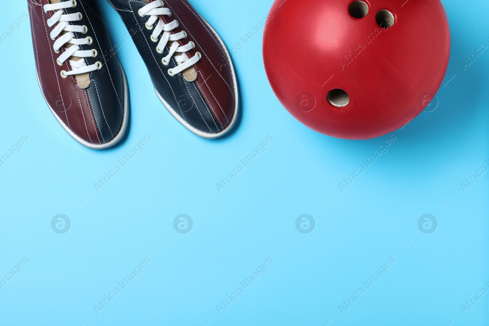 Photo of Bowling ball and shoes on light blue background, flat lay. Space for text