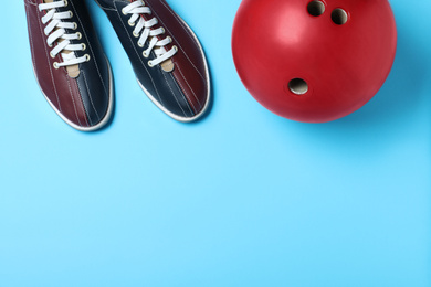 Photo of Bowling ball and shoes on light blue background, flat lay. Space for text