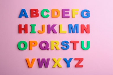 Photo of Colorful magnetic letters on pink background, flat lay. Alphabetical order