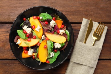 Photo of Delicious persimmon salad, knife and fork on wooden table, flat lay