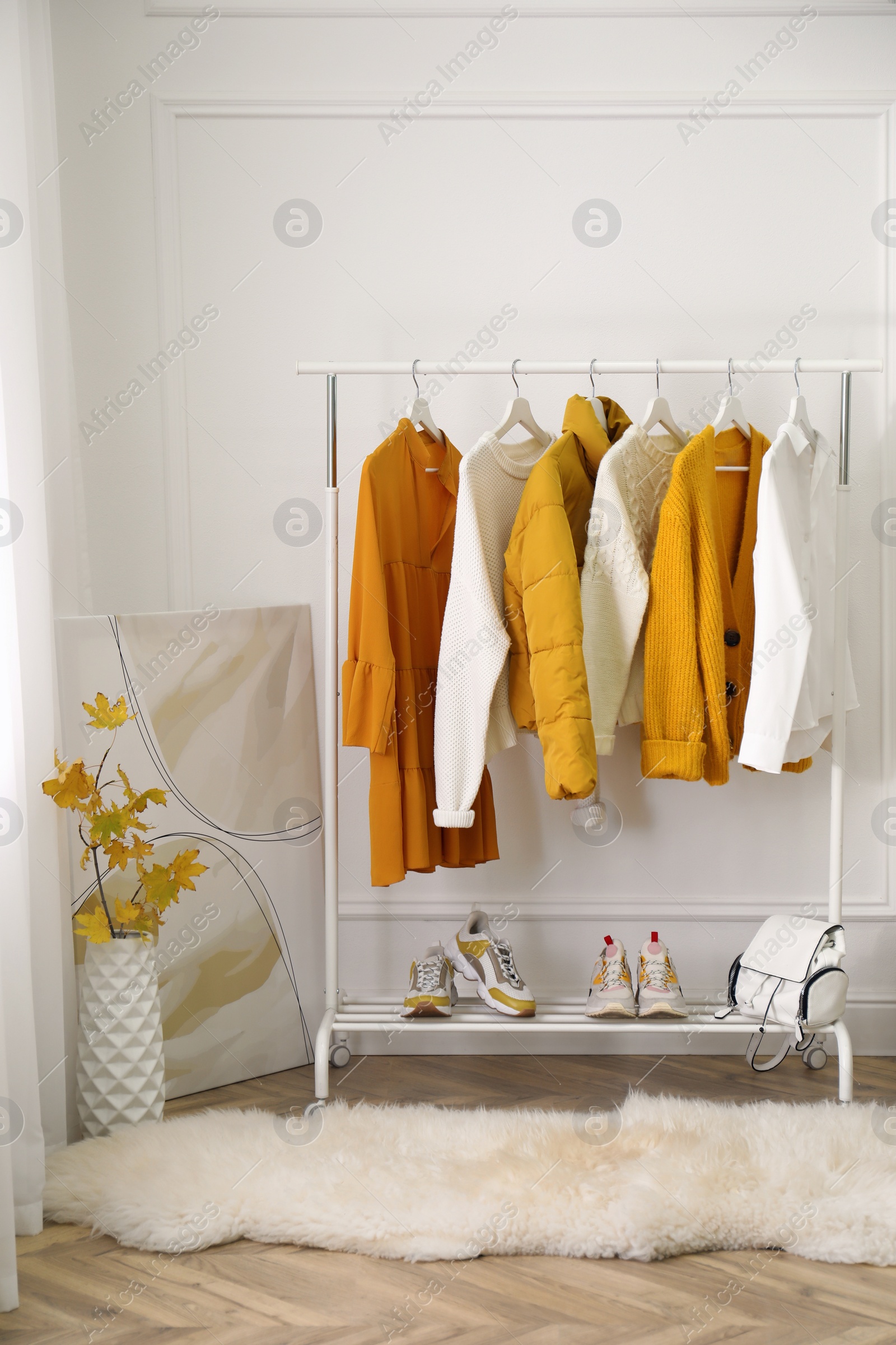 Photo of Rack with stylish warm clothes, shoes and accessories in modern dressing room