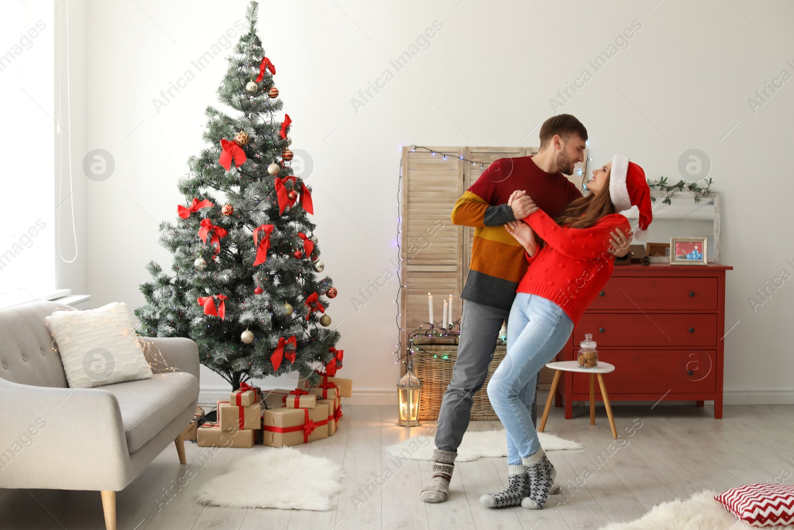 Photo of Happy young couple dancing near Christmas tree at home