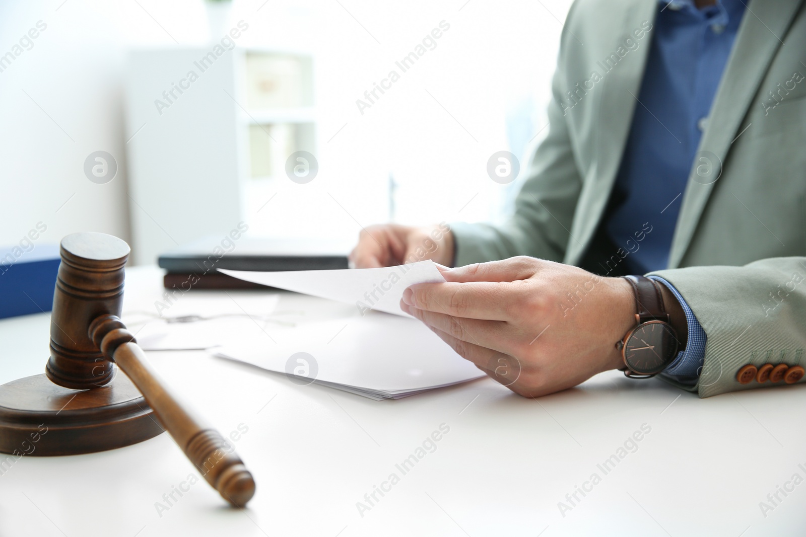 Photo of Notary working with papers and judge gavel on table, closeup. Law and justice concept