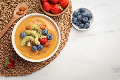 Delicious smoothie bowl with fresh berries, kiwi and nuts on white table, flat lay. Space for text