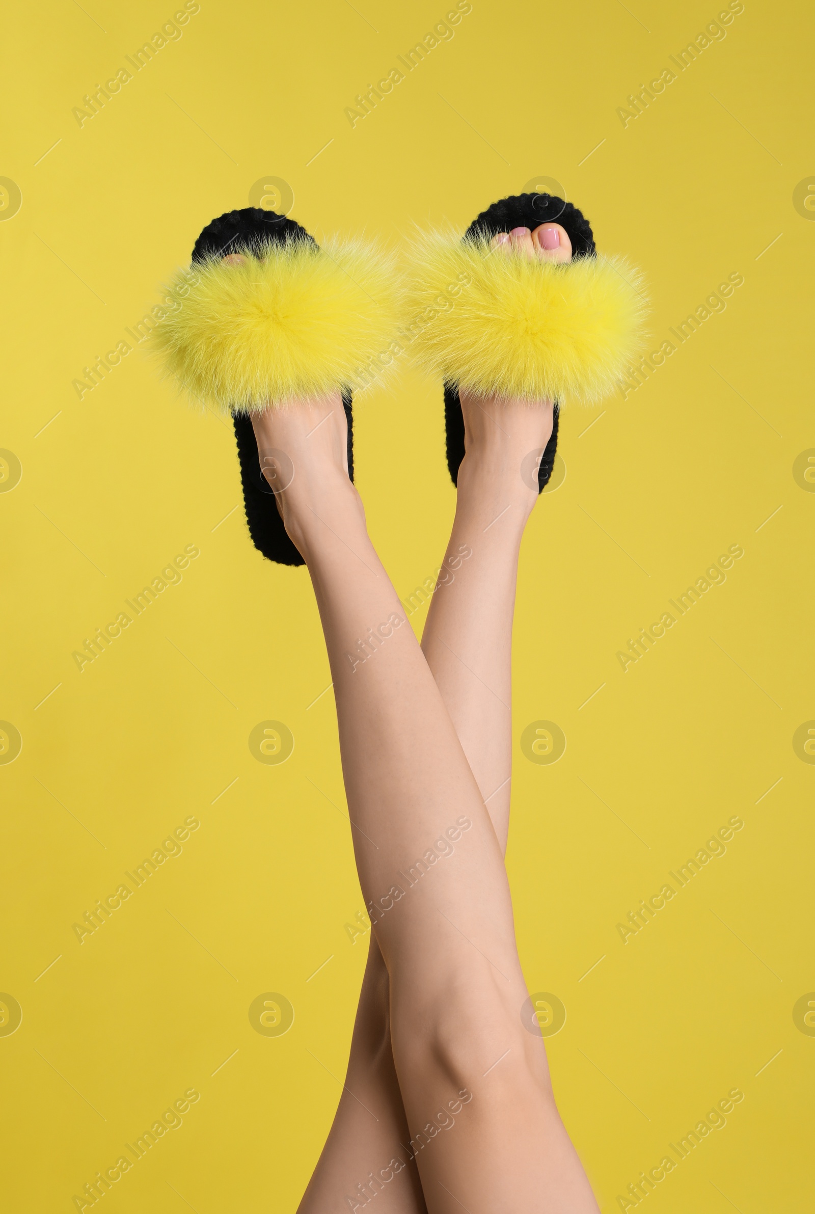 Photo of Woman wearing stylish slippers on yellow background, closeup