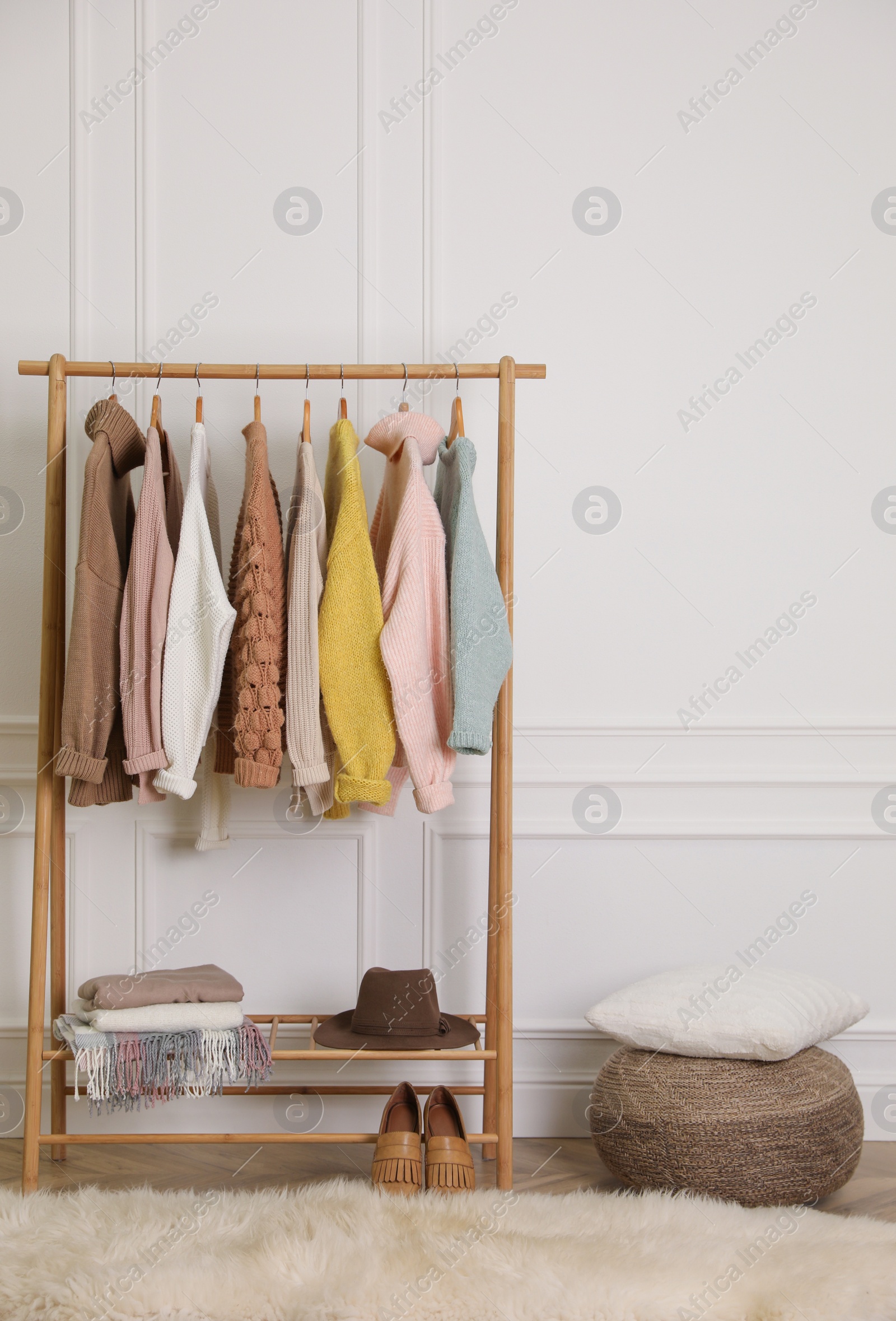 Photo of Stylish warm clothes on rack in dressing room interior