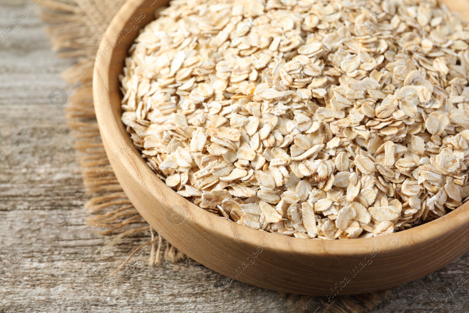 Photo of Bowl with oatmeal on wooden table, closeup