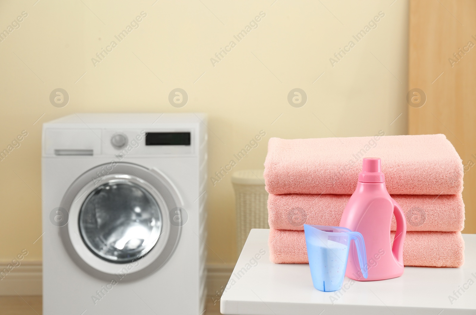 Photo of Stack of clean towels and detergents on table in laundry room. Space for text
