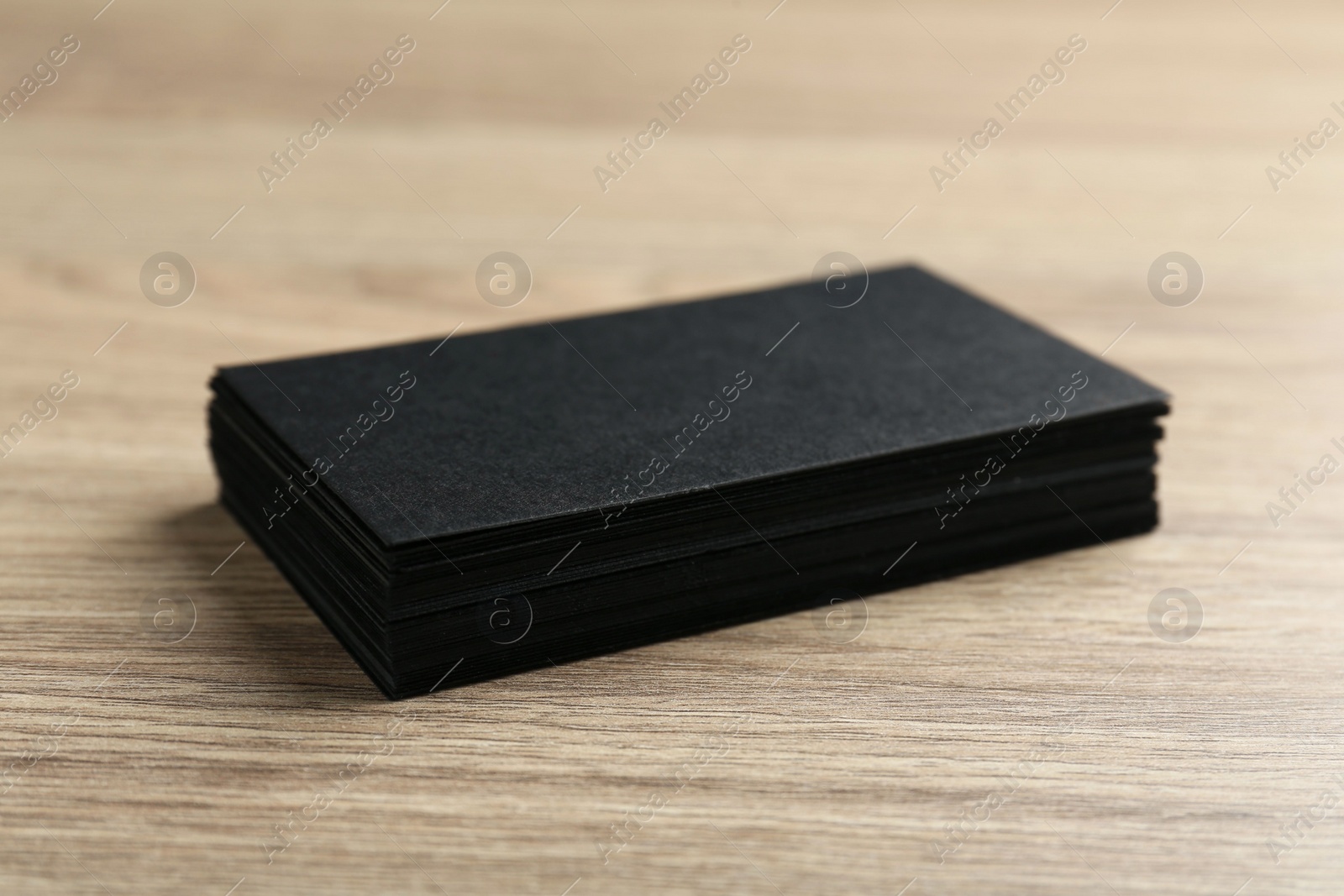 Photo of Blank black business cards on wooden table, closeup. Mockup for design