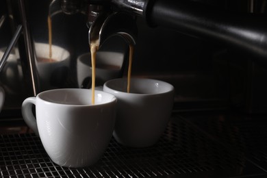 Photo of Making fresh aromatic espressos using professional coffee machine in cafe, closeup. Space for text