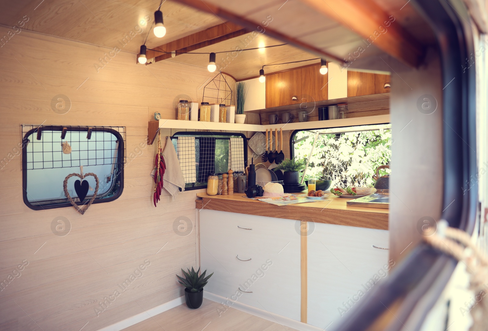 Photo of Stylish kitchen interior with different jars and utensils in modern trailer. Camping vacation