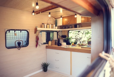 Photo of Stylish kitchen interior with different jars and utensils in modern trailer. Camping vacation
