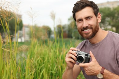 Photo of Man with camera outdoors, space for text. Interesting hobby