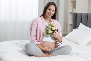 Photo of Beautiful pregnant woman with bouquet of roses in bedroom