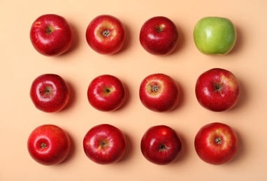Photo of Green apple among red ones on color background, top view. Be different