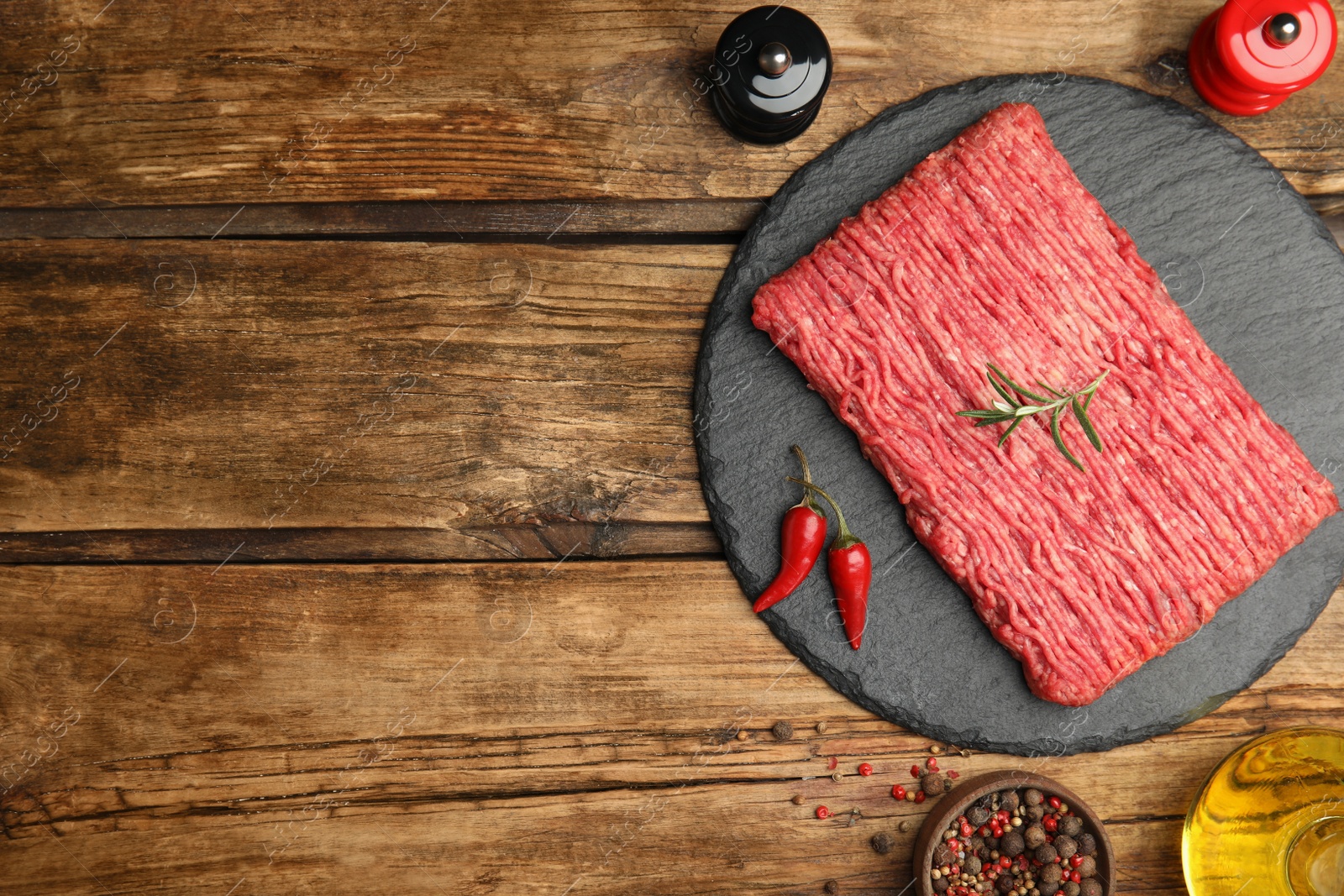 Photo of Raw fresh minced meat and other ingredients on wooden table, flat lay. Space for text