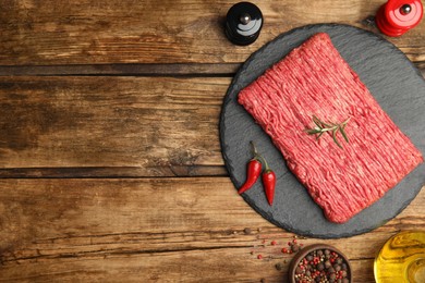 Raw fresh minced meat and other ingredients on wooden table, flat lay. Space for text