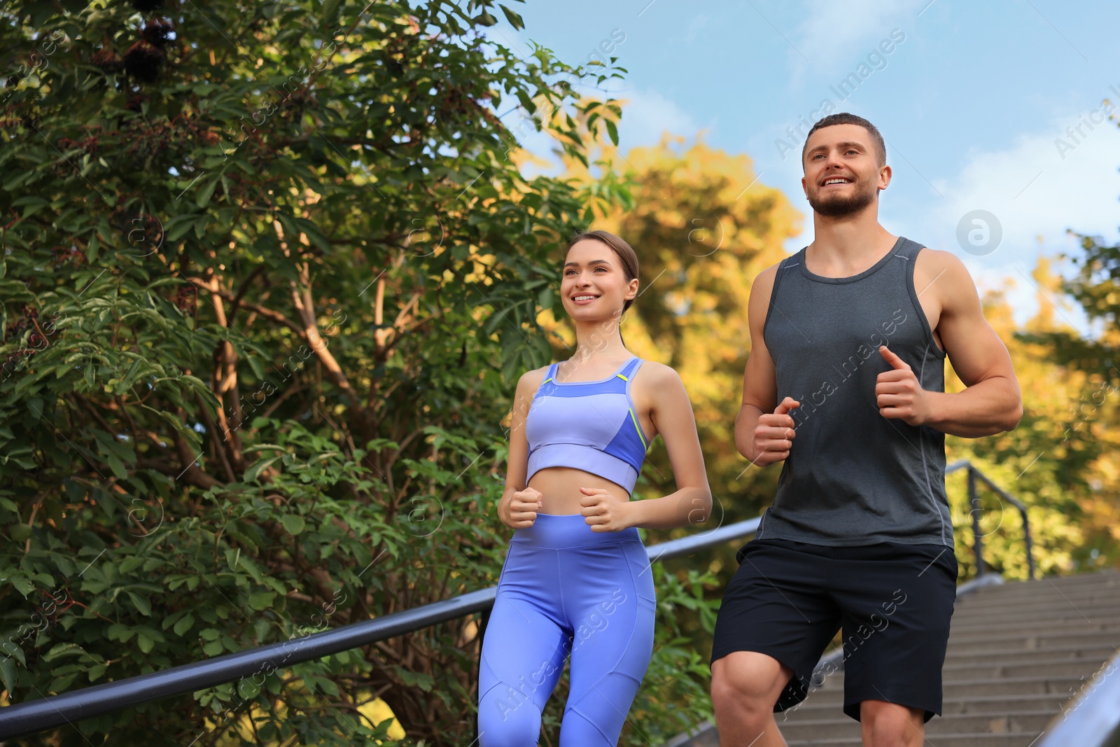 Photo of Attractive sporty couple running down stairs outdoors on sunny day