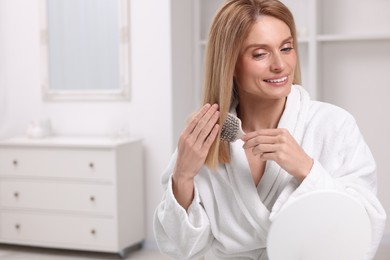 Beautiful woman brushing her hair in room