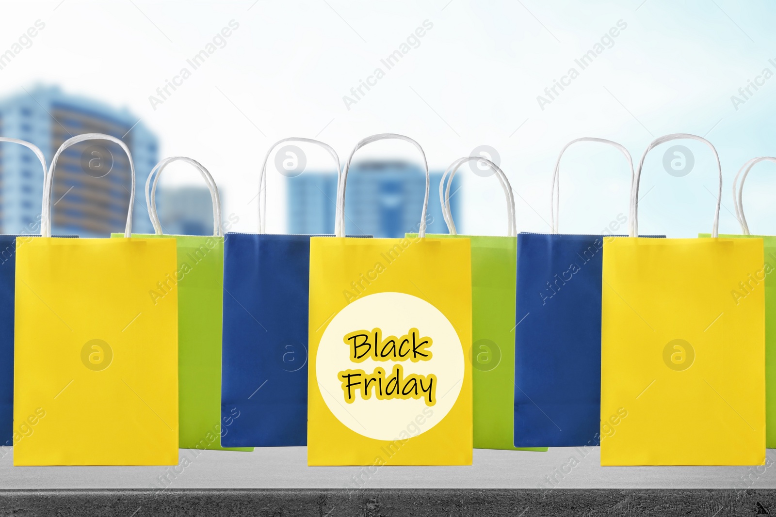 Image of Black Friday. Many shopping bags and blurred buildings on background