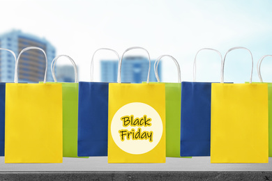 Image of Black Friday. Many shopping bags and blurred buildings on background