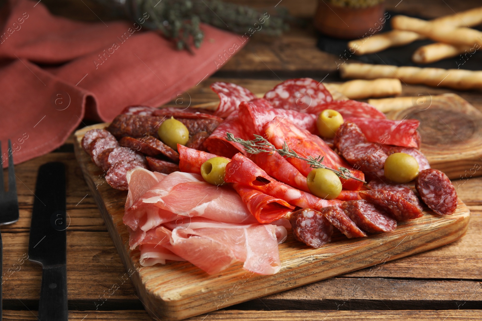 Photo of Tasty prosciutto with other delicacies served on wooden table