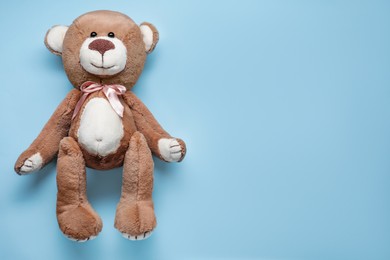 Photo of Cute teddy bear on light blue background, top view. Space for text